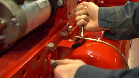 A worker in an assembly shop screws a nut with a wrench on an engine from a heav Stock Footage 148051236