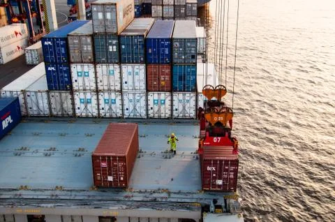 Worker assisting container uploading at dock Stock Photos
