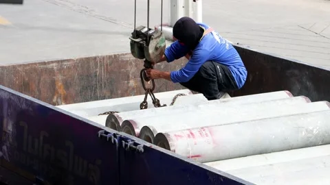 A worker attaches chains from a crane to concrete tubes Stock Footage 221740390