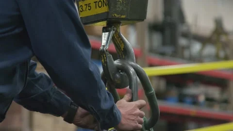 Worker attaches Large Chain Link to Crane Hook in yellow manufacturing facility Video stock 136784509