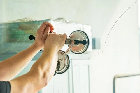 Worker attaching suction cup lifters to cracked window glass before removal from Stock Photos
