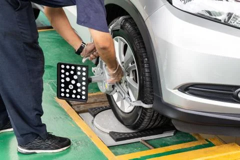 Worker attaching wheel alignment device equipment onto wheel car Foto stock