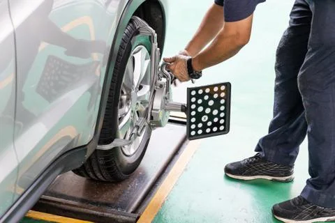 Worker attaching wheel alignment device equipment onto wheel car Stock Photos