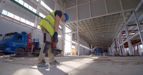 A worker in avest and a helmet with a hammer drill makes a hole  Stock Footage 161986393