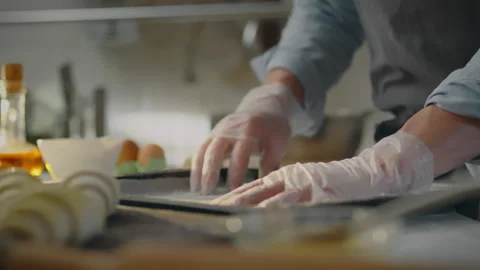 A worker in a bakery carefully prepares a baking tray by placing parchment p Stock Footage 270384091
