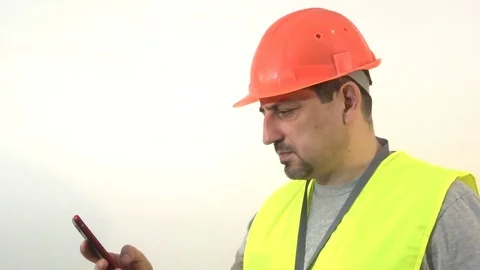 Worker with a beard and a helmet with a smartphone in his hand Stock Footage 93304193
