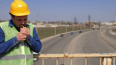 A worker with a beard and mustache is on the bridge smoking a cigarette. 4k Stock Footage 106356463
