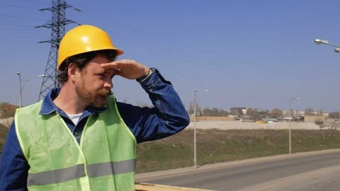 A worker with a beard and mustache in a yellow helmet stands on the bridge Stock Footage 106356579