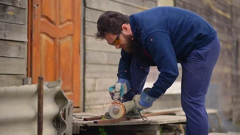 Worker with a beard and in yellow goggles saws the pipe with an abrasive machine Video stock 75206523