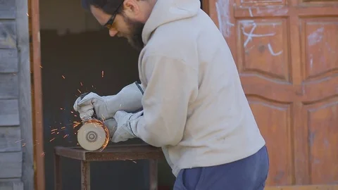 Worker with a beard puts on gloves and saws the pipe with an abrasive machine Stock Footage 75321336