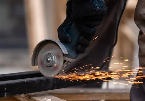 A worker in black protective gloves cutting a steel metal bar Stock Photos