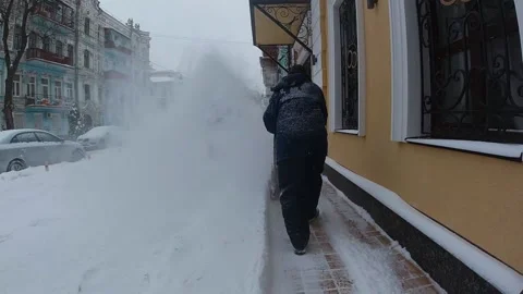 Worker in blu overalls removes snow with a red snow plow machine Stock Footage 219857259