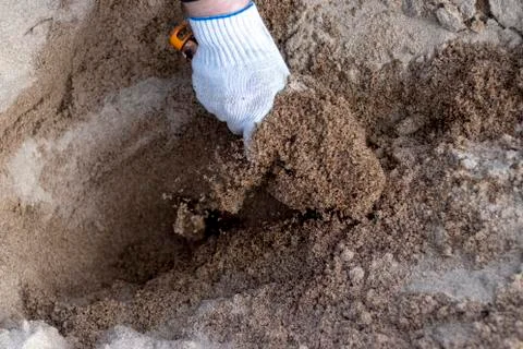 Worker in the blue boilersuit and work gloves with shovel is on the construct Stock Photos