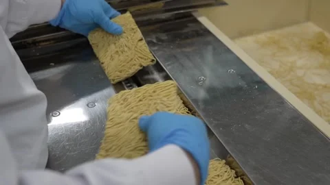 Worker with blue gloves handling and inspecting fresh noodle blocks on Vidéo 334690127