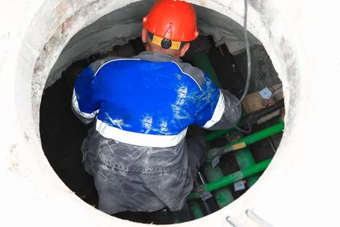 Worker in blue jacket and red helmet working inside a circular underground Stock Photos
