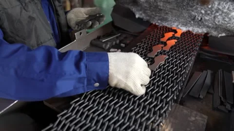 Worker in blue overalls guides glowing orange steel blanks along a mesh Vídeo Stock 346737970