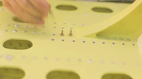 Worker in blue overalls installs rivets into holes pre-dipping them in liquid Stock Footage 66953992