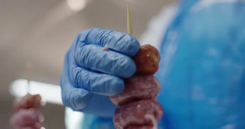 Worker in blue protective glove holding skewers of raw minced meat in a food Vídeo Stock 339959080