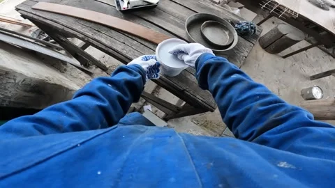Worker in blue protective overalls and gloves opens a can of brown varnish 스톡 동영상 335234244