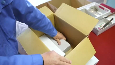 Worker in blue uniform packing white cutlery boxes into cardboard shipping Stock Footage 340277418