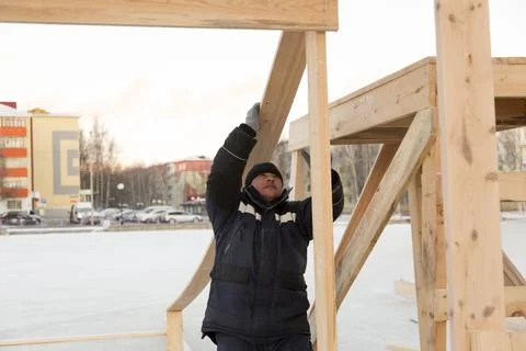 A worker with a board in his hand assembling the frame of a wooden slide Fotos Stock