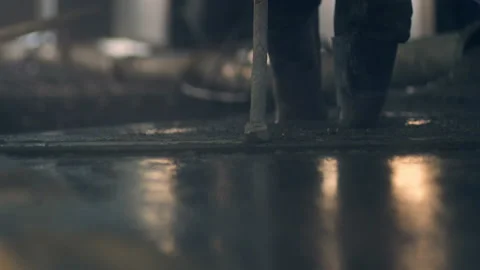 Worker in boots creates a smooth surface from concrete mass by mop Stock Footage 130260054
