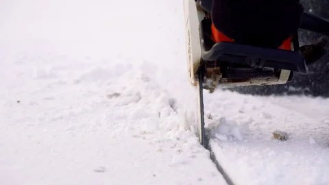 Worker in boots cut ice of frozen lake by chainsaw Stock Footage 72767859