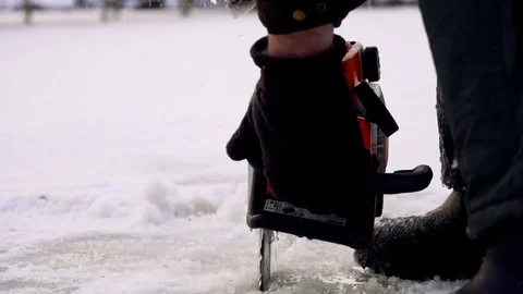 Worker in boots cut ice of frozen lake by chainsaw Stock Footage 72768437