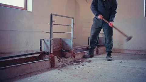 A Worker is Breaking Apart a Section of Concrete With a Sledgehammer - Static Stock Footage 304039796