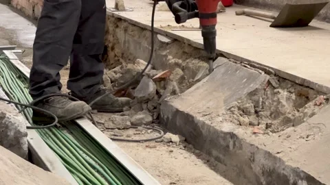 Worker breaking concrete with a hydraulic hammer at construction site Stock Footage 314044489