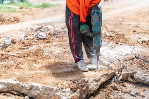 Worker breaking concrete with jackhammer. Stock Photos
