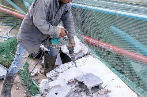 Worker breaking concrete using jackhammer. Stock Photos
