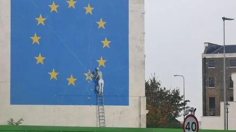 A worker breaks away at one of the golden stars from the eu flag graffity Stock Footage 102563526