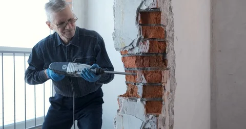 Worker breaks a brick wall hammer in house. Redevelopment in room open space Stock Footage 128230089