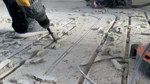 A worker breaks a concrete floor during construction work with a jackhammer Video stock 223203985