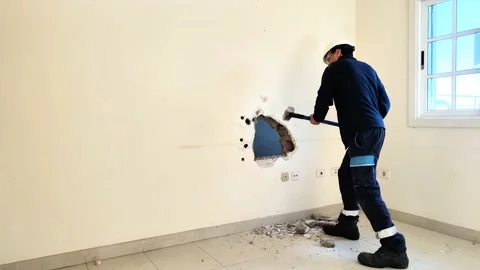 Worker breaks a wall of a house to do construction and remodeling works Stock Footage 201543125