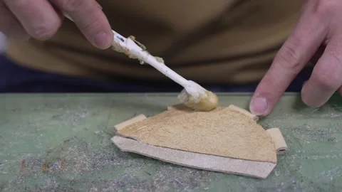 Worker brushing adhesive glue onto a suede leather piece on the workshop bench Stock Footage 340156134