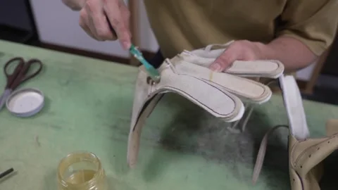 Worker brushing glue onto the interior leather parts of a baseball glove at the Stock Footage 340565705