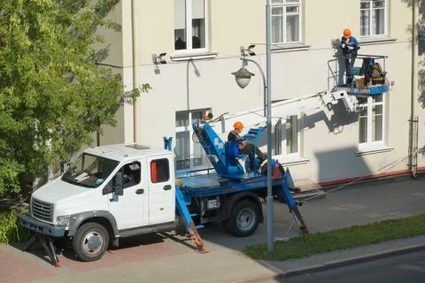 A worker in the bucket of a crane is installing lighting on the facade of the Stock Photos