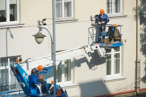 A worker in the bucket of a crane is installing lighting on the facade of the Stock Photos