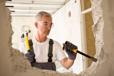 Worker builder demolish wall with tool Stock Photos