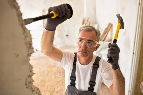 Worker builder demolish wall with tool Stock Photos