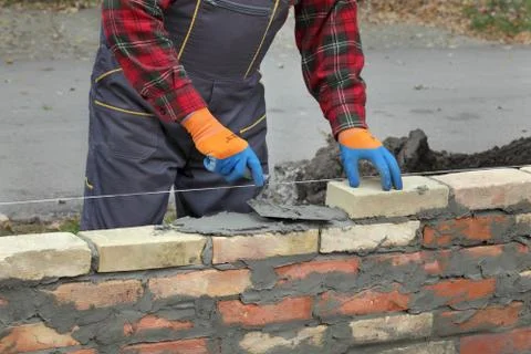 Worker building brick wall using trowel Stock Photos