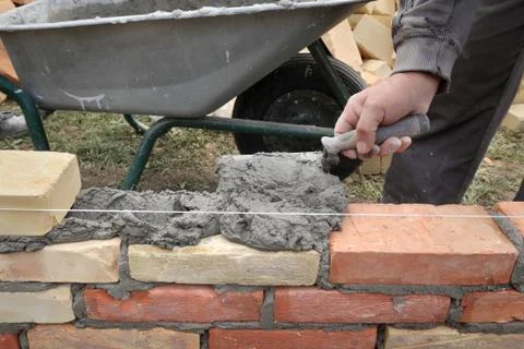 Worker building brick wall using trowel Stockfoto's
