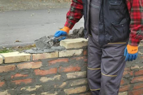 Worker building brick wall using trowel Фото