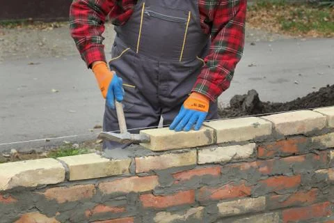 Worker building brick wall using hammer Stock Photos