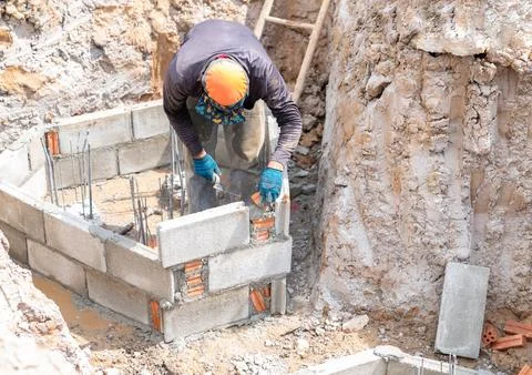 The worker is building a triangular foundation formwork with bricks to cast.. Stock Photos