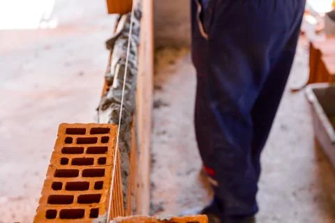 Worker is building wall with red blocks and mortar Fotos de archivo