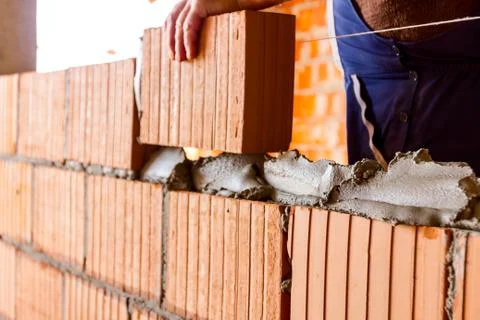 Worker is building wall with red blocks and mortar Fotos de archivo