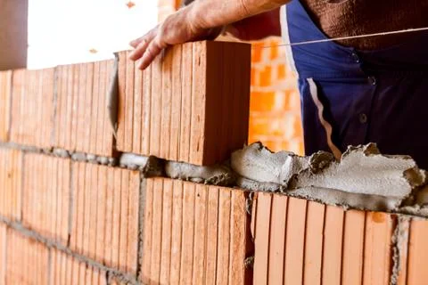 Worker is building wall with red blocks and mortar Fotos de archivo